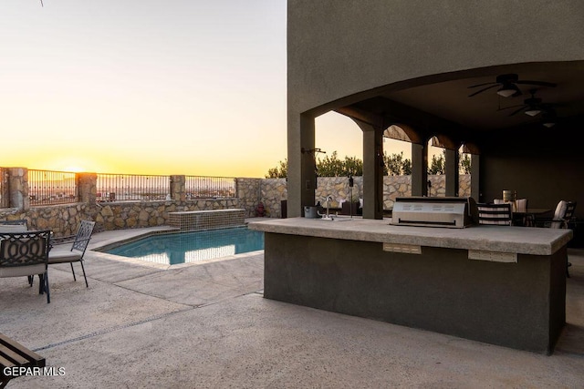 pool at dusk with a fenced in pool, grilling area, an outdoor kitchen, a patio area, and fence