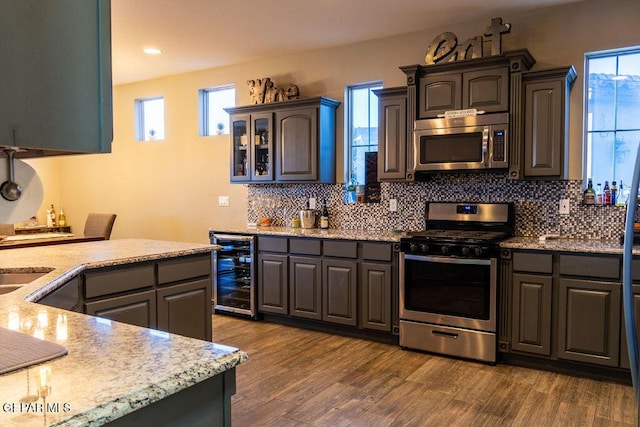 kitchen with stainless steel appliances, beverage cooler, dark wood-type flooring, and backsplash