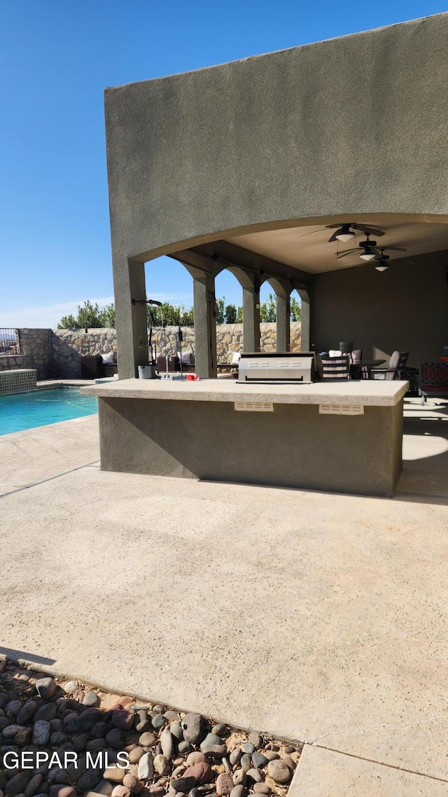 exterior space featuring area for grilling, a ceiling fan, and an outdoor pool