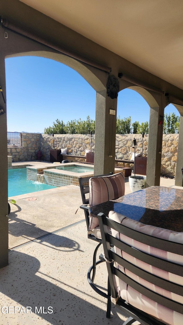 view of patio / terrace featuring outdoor dining space, a pool with connected hot tub, and a fenced backyard