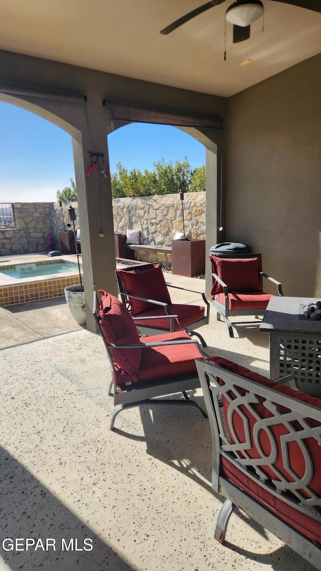 view of patio / terrace featuring a fenced backyard, ceiling fan, and an in ground hot tub