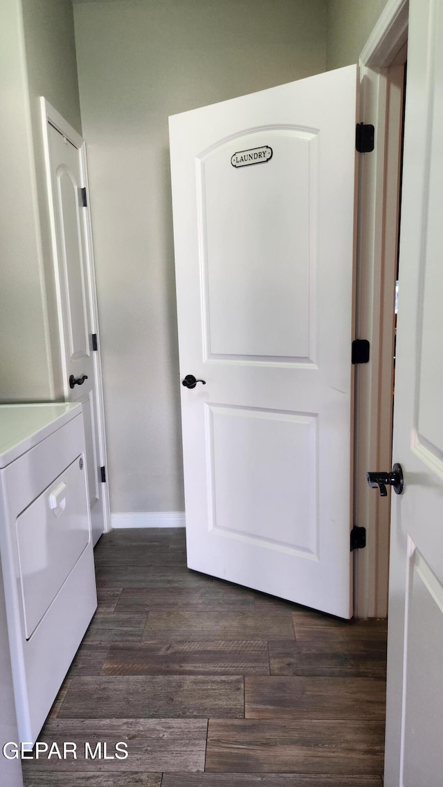 clothes washing area with washer / dryer, laundry area, dark wood finished floors, and baseboards