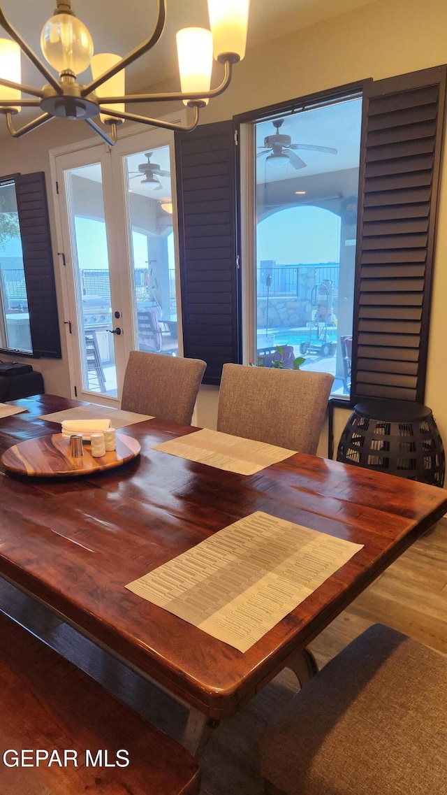 dining space featuring a wealth of natural light, wood finished floors, and ceiling fan with notable chandelier