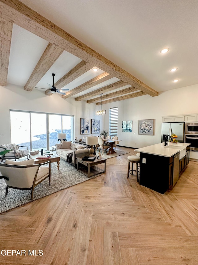 living room with recessed lighting, beamed ceiling, and ceiling fan with notable chandelier