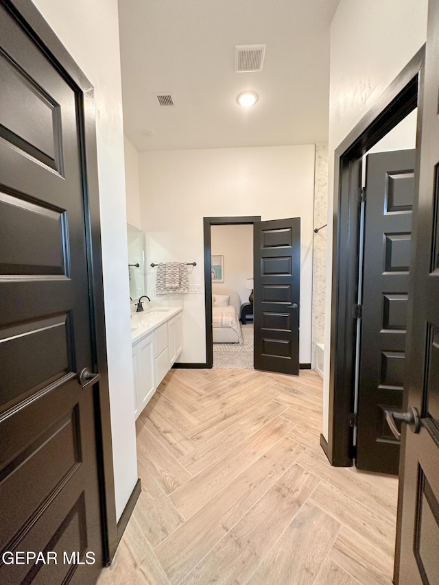 ensuite bathroom with vanity, ensuite bath, visible vents, and baseboards