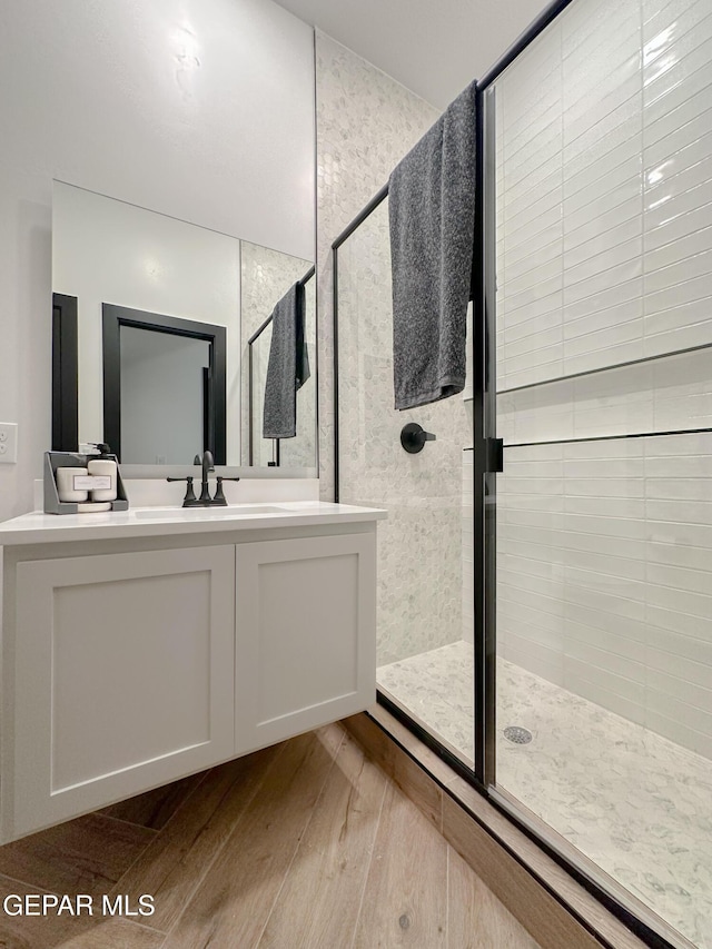 bathroom featuring wood finished floors, a shower stall, and vanity