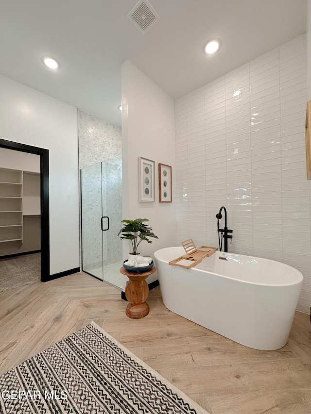 bathroom featuring visible vents, a soaking tub, wood finished floors, a shower stall, and recessed lighting