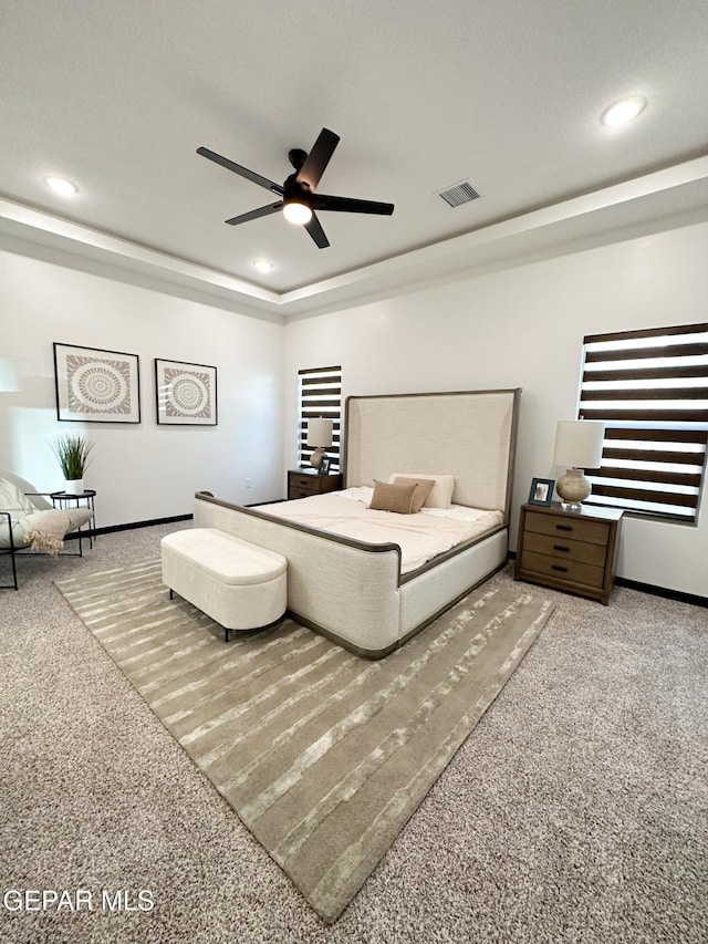 bedroom with a tray ceiling, carpet, visible vents, and recessed lighting