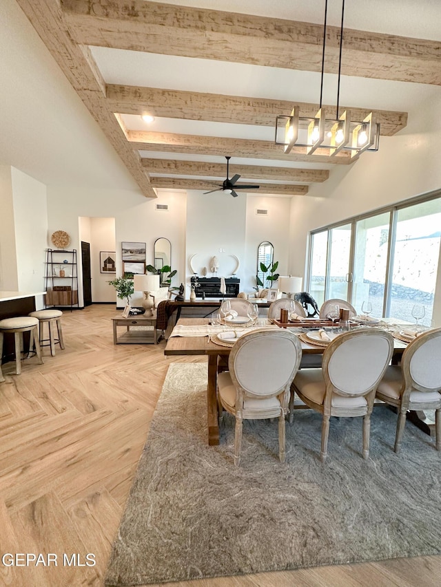 dining area featuring a towering ceiling, a ceiling fan, and beamed ceiling