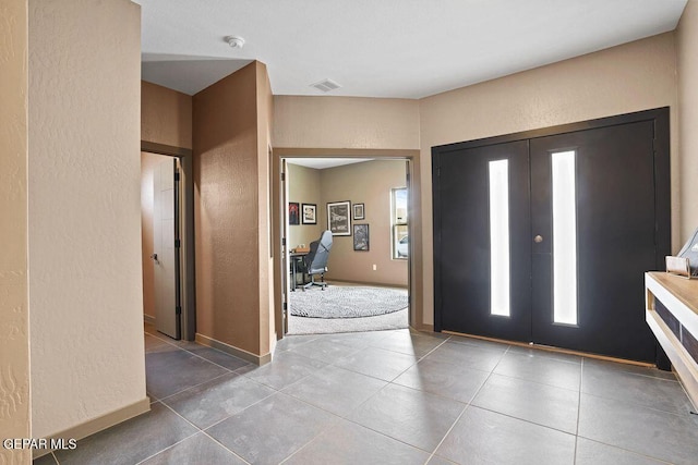 tiled entrance foyer featuring french doors, visible vents, plenty of natural light, and baseboards