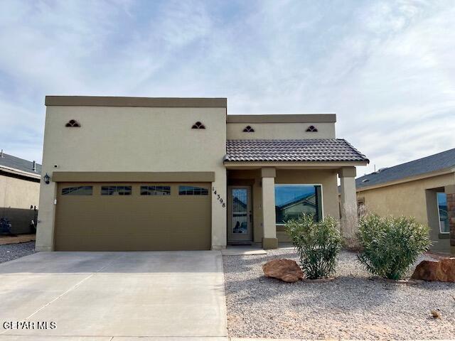 adobe home featuring a garage, a tile roof, driveway, and stucco siding