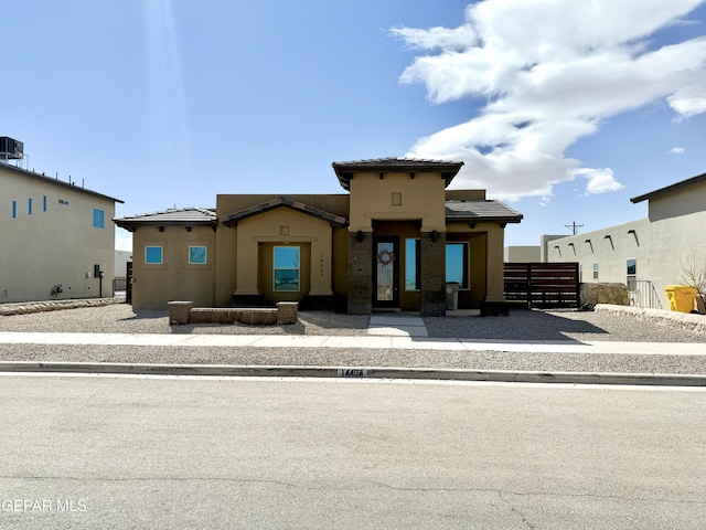 view of front of house with central AC unit, stucco siding, a tiled roof, and fence