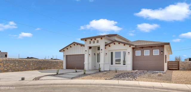 view of front of house featuring a garage, driveway, board and batten siding, and fence