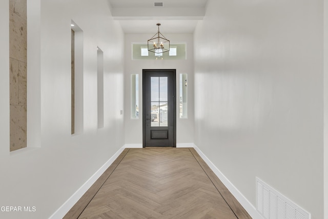 foyer entrance with an inviting chandelier, visible vents, and baseboards