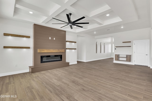 unfurnished living room with coffered ceiling, a fireplace, baseboards, and wood finished floors