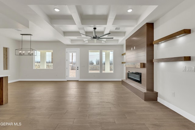 unfurnished living room with a fireplace, wood finished floors, coffered ceiling, baseboards, and ceiling fan with notable chandelier