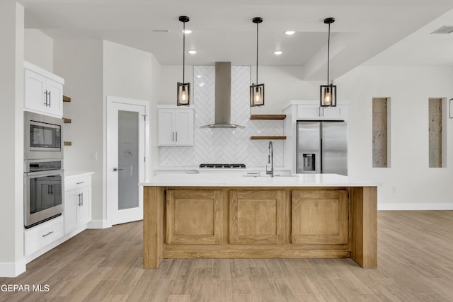 kitchen with light countertops, appliances with stainless steel finishes, wall chimney exhaust hood, open shelves, and tasteful backsplash