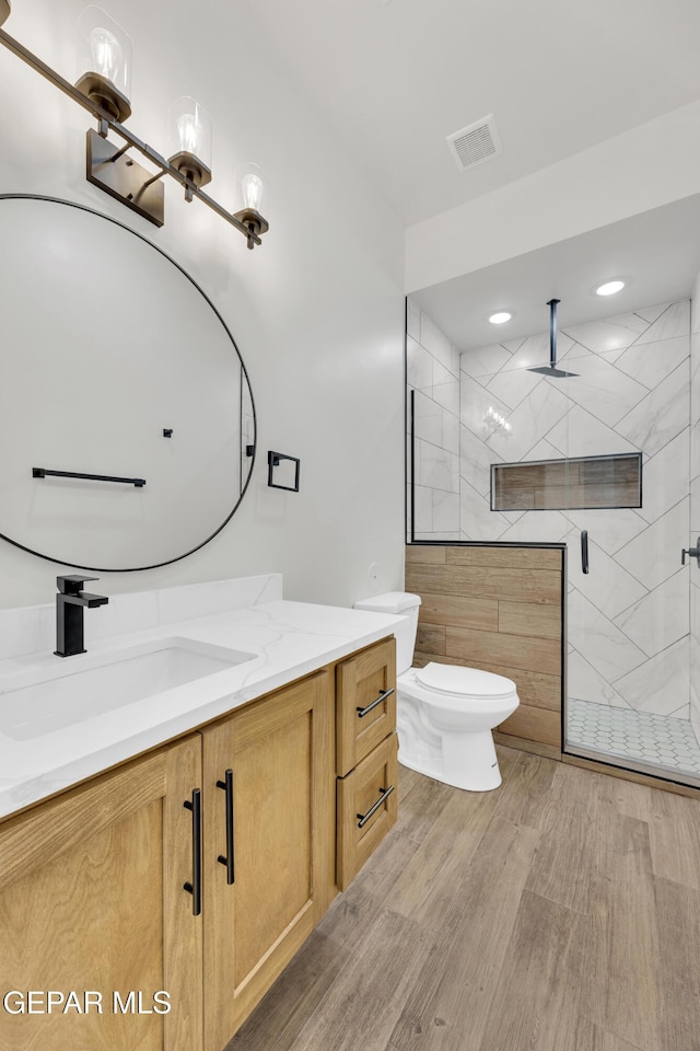 full bath featuring visible vents, toilet, wood finished floors, vanity, and a shower stall