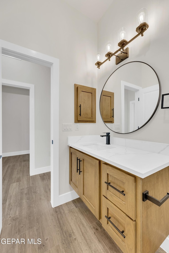 bathroom with baseboards, wood finished floors, and vanity