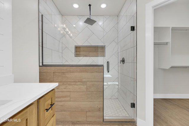 full bathroom with a stall shower, baseboards, wood finished floors, vanity, and recessed lighting