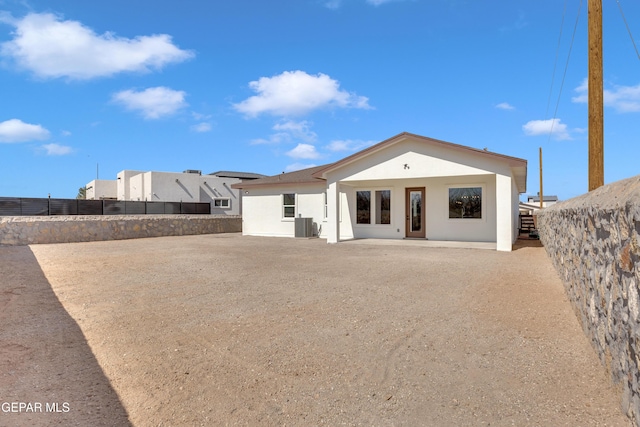 rear view of house featuring a patio area, a fenced backyard, central AC, and stucco siding