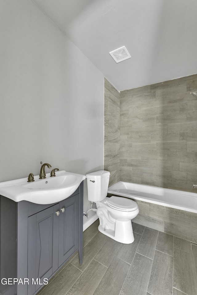 bathroom with tiled bath, toilet, visible vents, vanity, and a tile shower