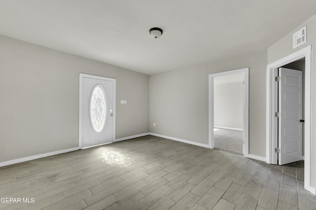 entryway featuring visible vents, baseboards, and wood finished floors