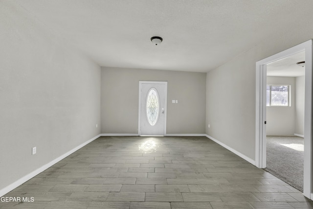 entryway featuring a textured ceiling, baseboards, and wood finished floors