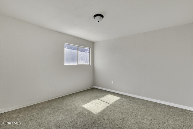 spare room featuring carpet and baseboards