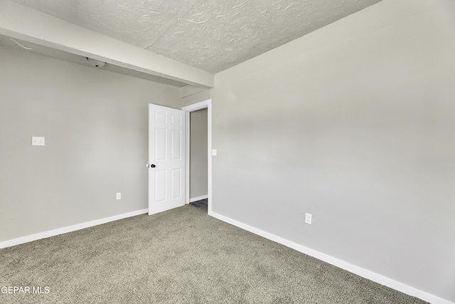 unfurnished room with a textured ceiling, baseboards, carpet flooring, and beamed ceiling