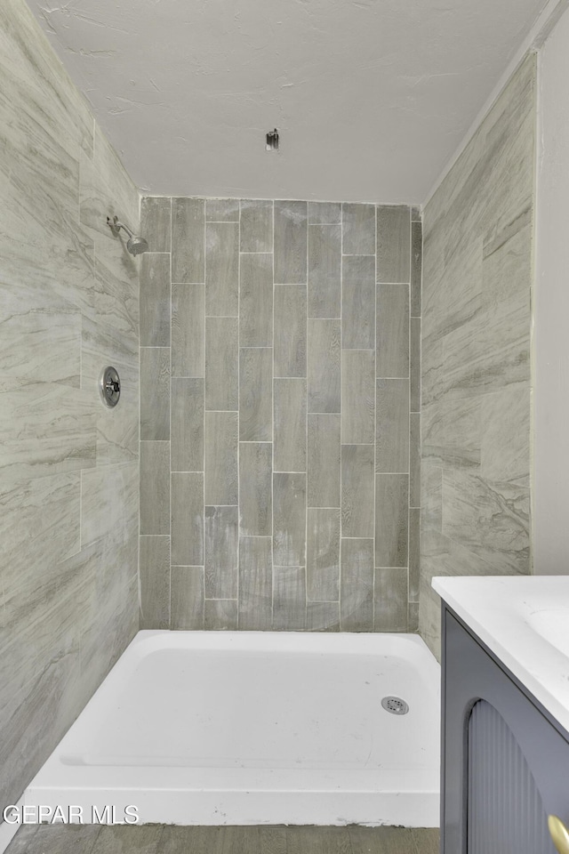 bathroom with tiled shower and vanity