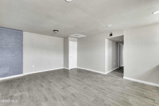 empty room with a textured ceiling, baseboards, and wood finished floors