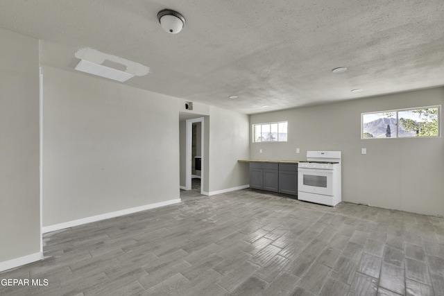 kitchen with light wood-style flooring, white gas range oven, a textured ceiling, and gray cabinetry