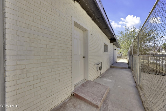 view of side of home featuring fence and brick siding