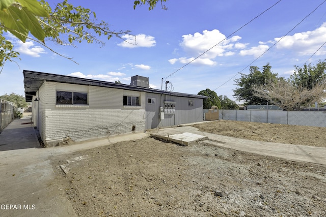 back of property featuring a chimney, fence, and brick siding