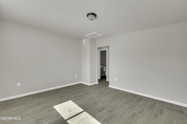 empty room with baseboards, visible vents, and wood finish floors