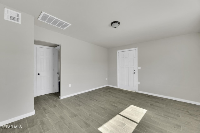 spare room with wood finished floors, visible vents, and baseboards