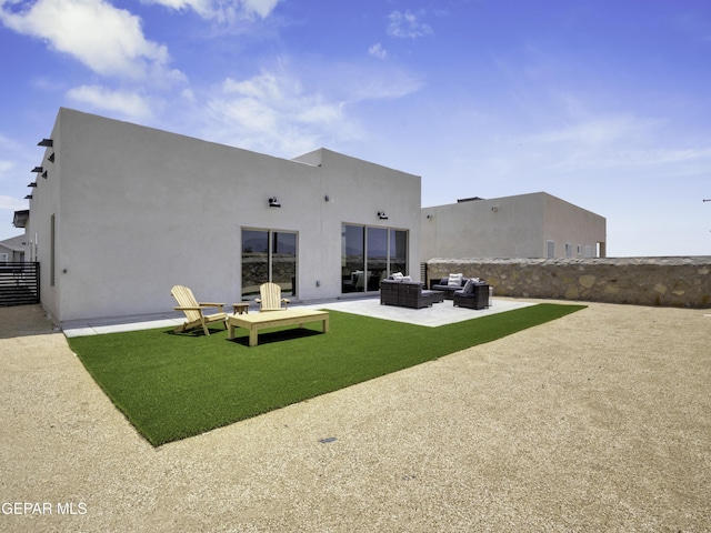 rear view of property featuring a patio area, outdoor lounge area, and stucco siding