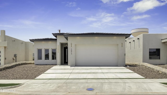 view of front of home featuring concrete driveway, a tiled roof, an attached garage, and stucco siding