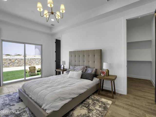 bedroom with access to exterior, a notable chandelier, visible vents, wood finished floors, and baseboards