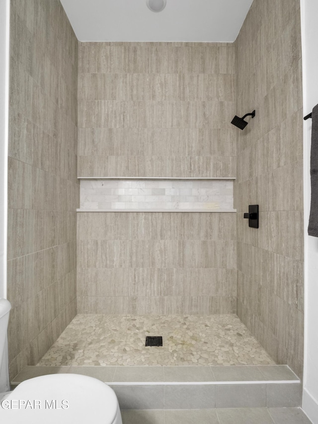 bathroom with tiled shower and toilet