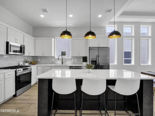 kitchen with stainless steel appliances, tasteful backsplash, a sink, and visible vents