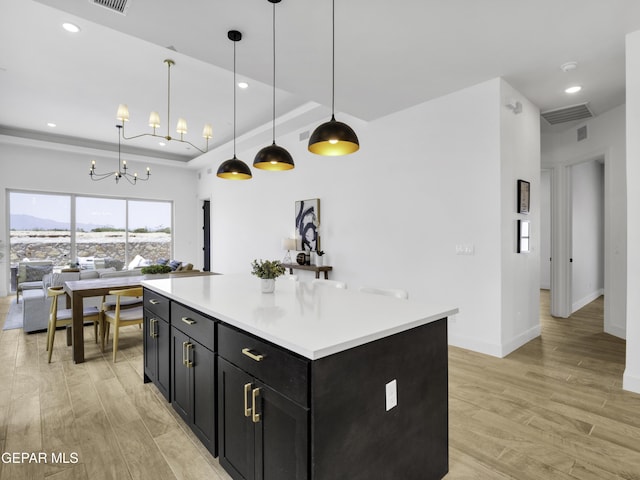 kitchen with light wood-style floors, light countertops, a raised ceiling, and dark cabinetry