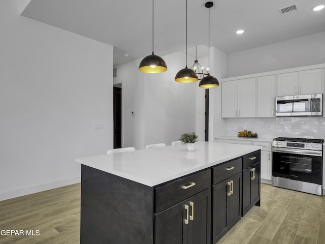 kitchen with stainless steel appliances, tasteful backsplash, light countertops, visible vents, and white cabinetry