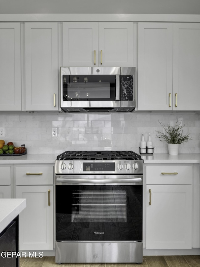 kitchen with white cabinetry, appliances with stainless steel finishes, light countertops, and backsplash