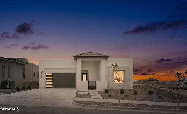 contemporary home with a garage, concrete driveway, central air condition unit, and stucco siding