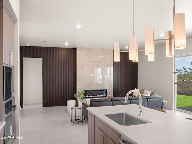 kitchen with oven, a fireplace, a sink, open floor plan, and light countertops