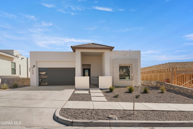 view of front facade with an attached garage, fence, concrete driveway, and stucco siding