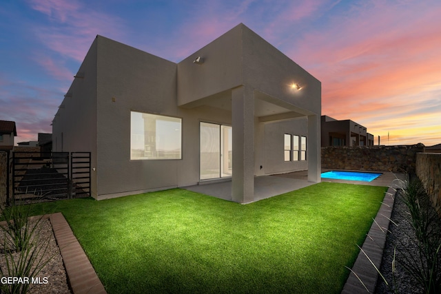 back of property at dusk with a patio area and stucco siding