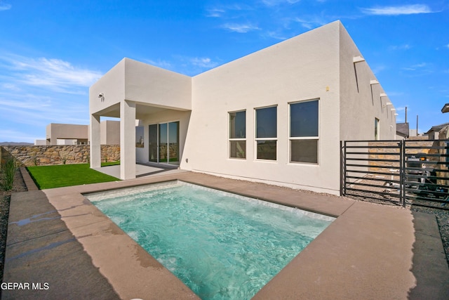 rear view of house with stucco siding, a patio, and fence